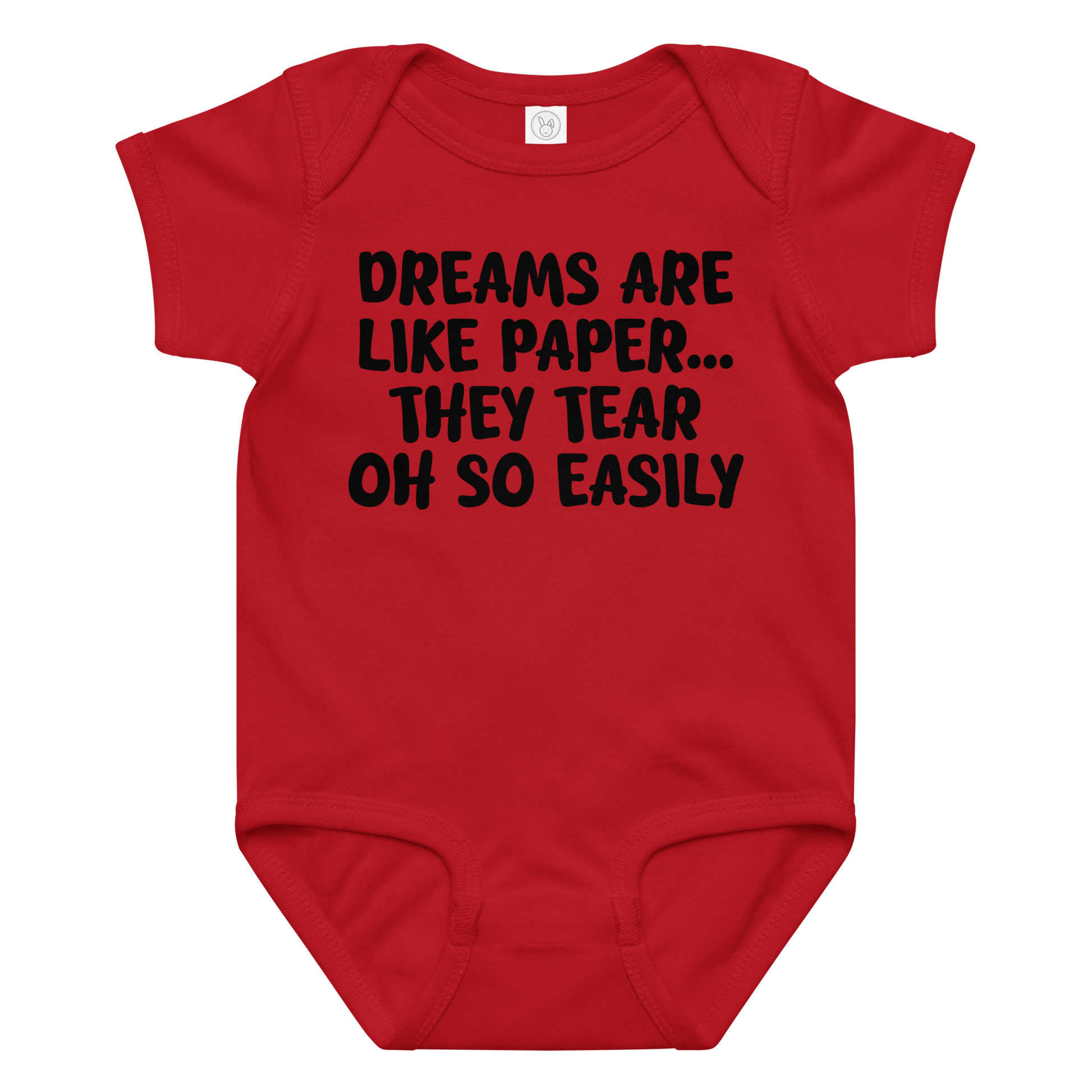 "Dreams are like paper, they tear oh so easily" printed on a red baby jersey bodysuit laying on a flat surface amongst other clothes