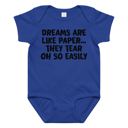 "Dreams are like paper, they tear oh so easily" printed on a royal baby jersey bodysuit laying on a flat surface amongst other clothes