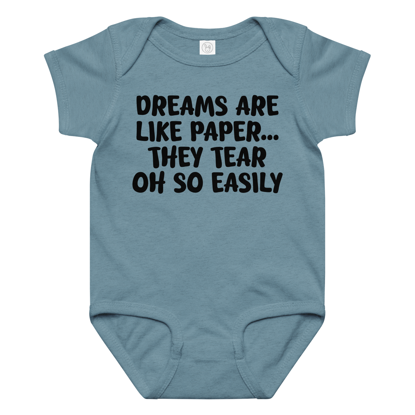 "Dreams are like paper, they tear oh so easily" printed on a vintage indigo baby jersey bodysuit laying on a flat surface amongst other clothes