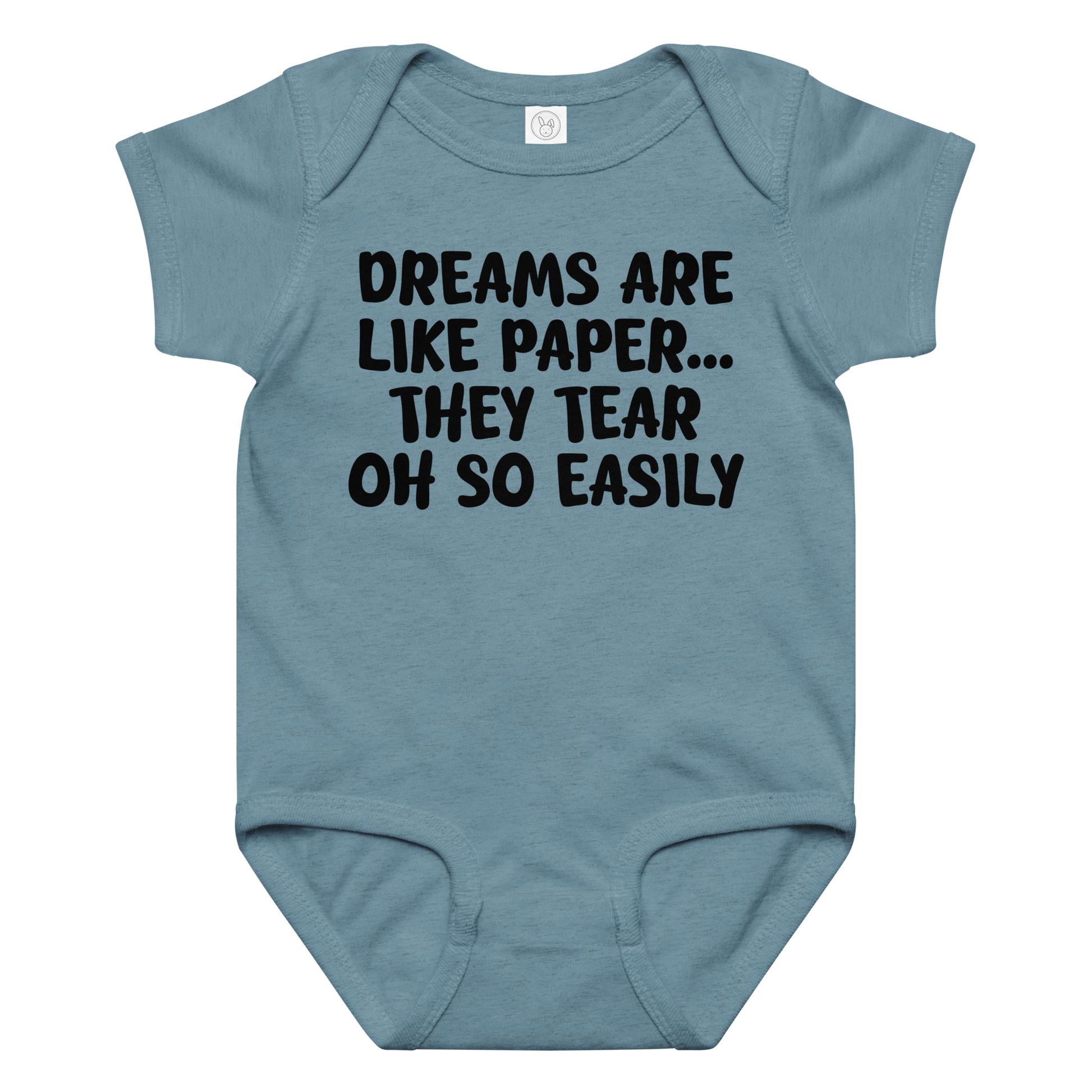 "Dreams are like paper, they tear oh so easily" printed on a vintage indigo baby jersey bodysuit laying on a flat surface amongst other clothes