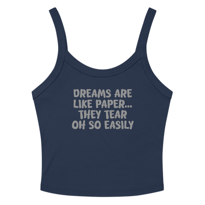 "Dreams are like paper, they tear oh so easily" printed on a solid navy blend women's micro-rib tanktop laying on a flat surface amongst sunglasses and shorts