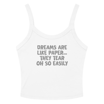 "Dreams are like paper, they tear oh so easily" printed on a solid white blend women's micro-rib tanktop laying on a flat surface amongst sunglasses and shorts