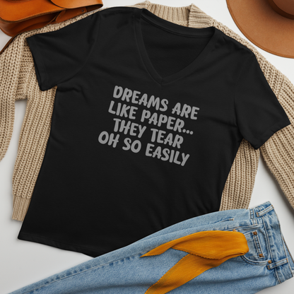 "Dreams are like paper, they tear oh so easily" printed on a solid black blend women's relaxed v-neck t-shirt laying on a flat surface amongst other clothes