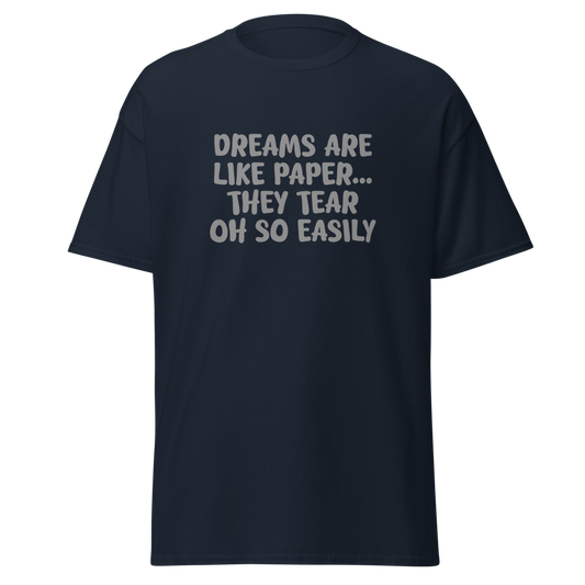 "Dreams are like paper, they tear oh so easily" printed on a navy unisex classic tee laying on a flat surface