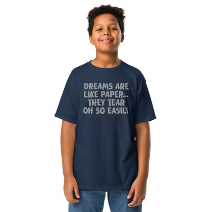 "Dreams are like paper, they tear oh so easily" printed on a navy youth classic tee worn by a male