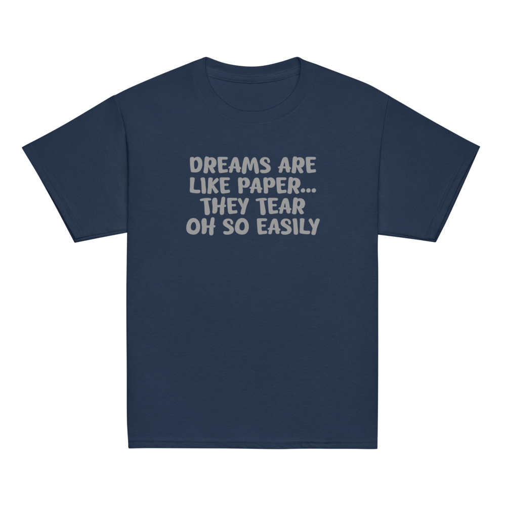 "Dreams are like paper, they tear oh so easily" printed on a navy youth classic tee laying on a flat surface