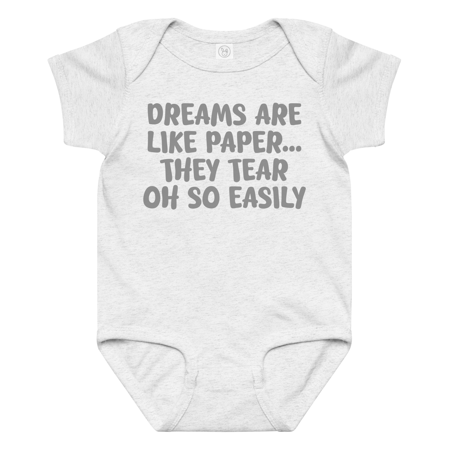 "Dreams are like paper, they tear oh so easily" printed on a ash baby jersey bodysuit laying on a flat surface amongst other clothes