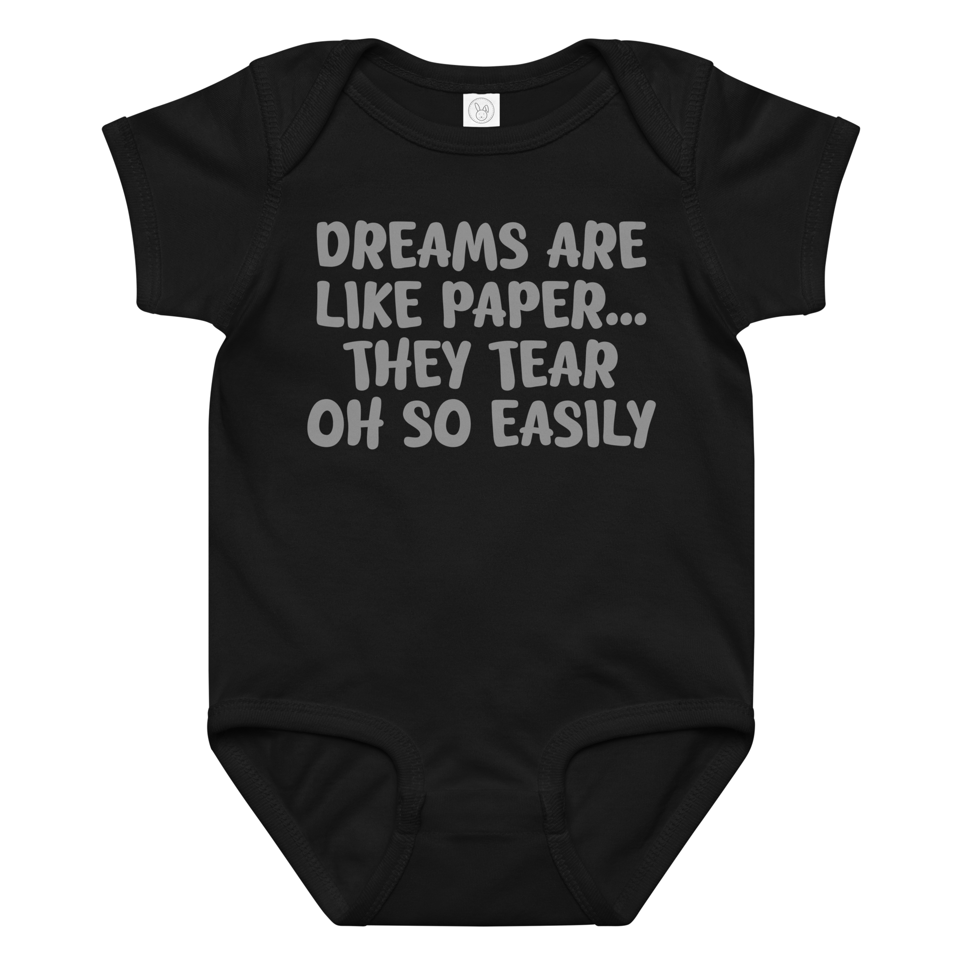 "Dreams are like paper, they tear oh so easily" printed on a black baby jersey bodysuit laying on a flat surface amongst other clothes