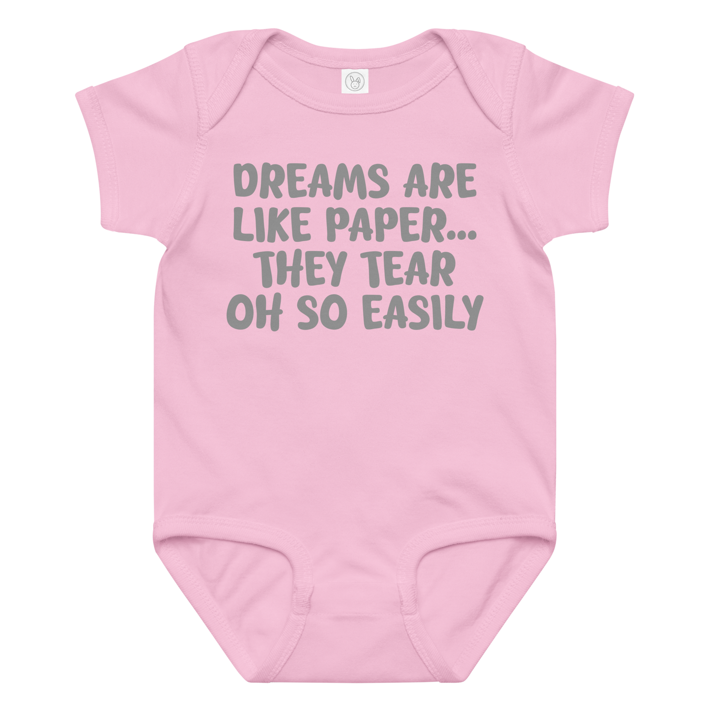 "Dreams are like paper, they tear oh so easily" printed on a pink baby jersey bodysuit laying on a flat surface amongst other clothes