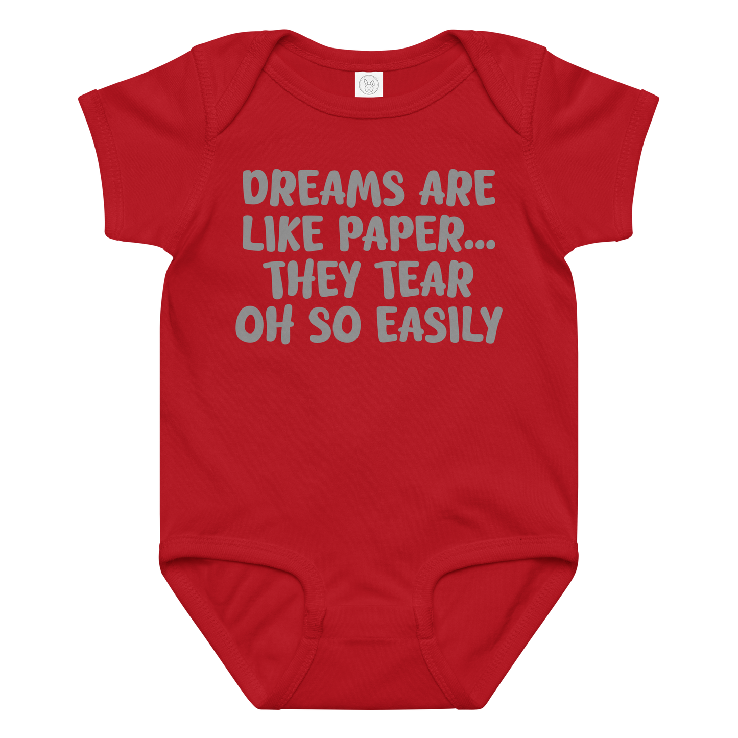 "Dreams are like paper, they tear oh so easily" printed on a red baby jersey bodysuit laying on a flat surface amongst other clothes