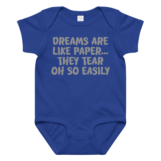 "Dreams are like paper, they tear oh so easily" printed on a royal baby jersey bodysuit laying on a flat surface amongst other clothes