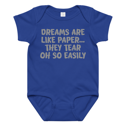 "Dreams are like paper, they tear oh so easily" printed on a royal baby jersey bodysuit laying on a flat surface amongst other clothes