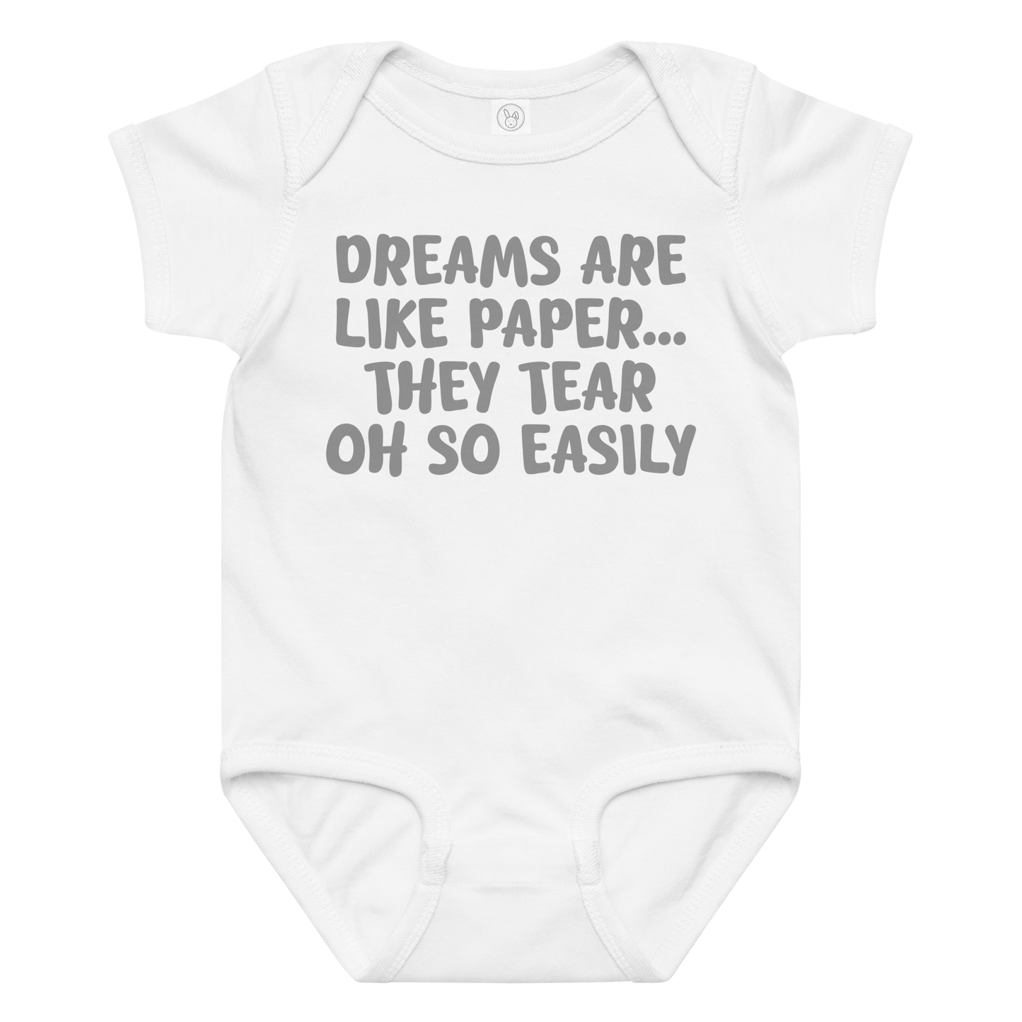 "Dreams are like paper, they tear oh so easily" printed on a white baby jersey bodysuit laying on a flat surface amongst other clothes