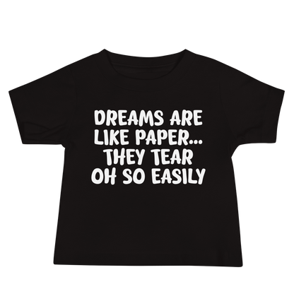 "Dreams are like paper, they tear oh so easily" printed on a black baby jersey short sleeve tee laying on a flat surface