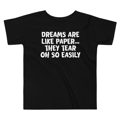"Dreams are like paper, they tear oh so easily" printed on a black toddler short sleeve tee laying on a flat surface