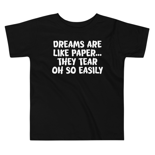 "Dreams are like paper, they tear oh so easily" printed on a black toddler short sleeve tee laying on a flat surface
