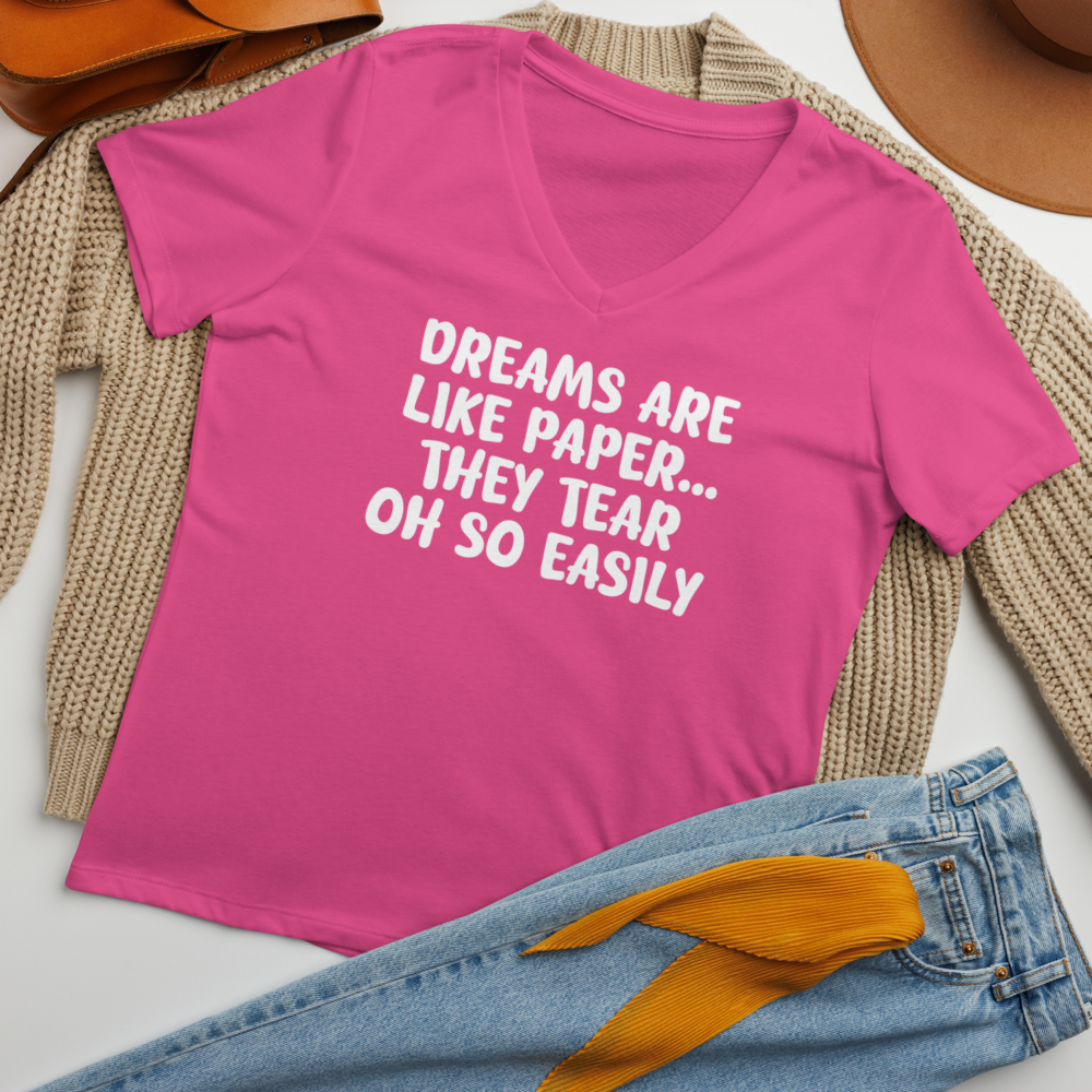 "Dreams are like paper, they tear oh so easily" printed on a berry women's relaxed v-neck t-shirt laying on a flat surface amongst other clothes