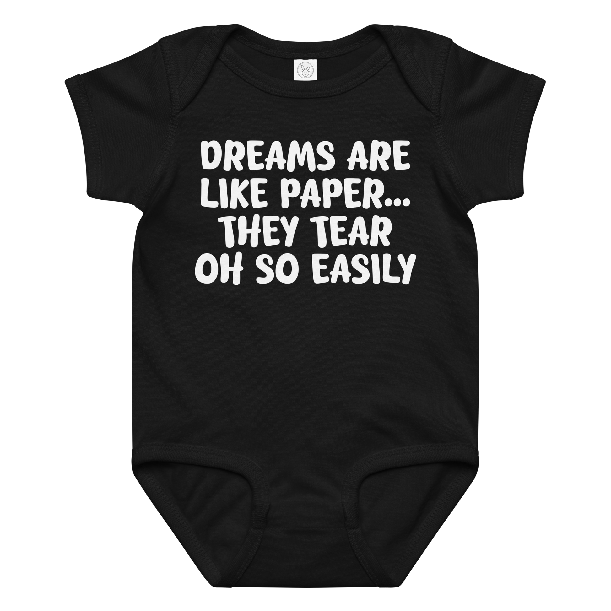 "Dreams are like paper, they tear oh so easily" printed on a black baby jersey bodysuit laying on a flat surface amongst other clothes