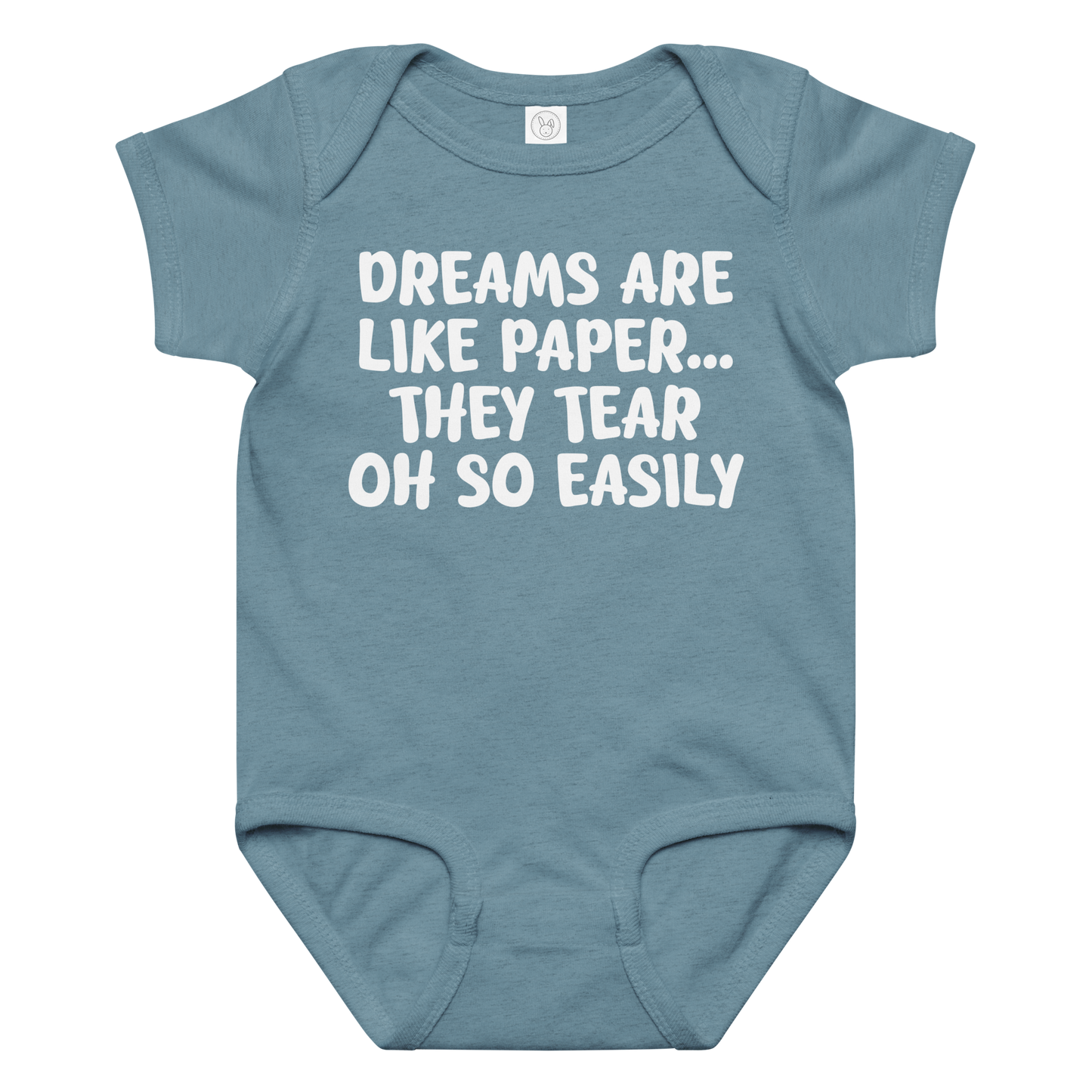 "Dreams are like paper, they tear oh so easily" printed on a vintage indigo baby jersey bodysuit laying on a flat surface amongst other clothes