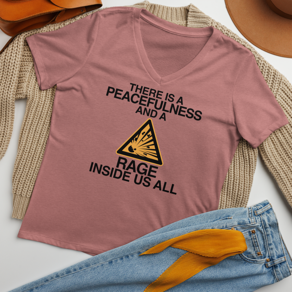 "There is a peacefulness and a rage inside us all" printed on a heather mauve women's relaxed v-neck t-shirt laying on a flat surface amongst other clothes