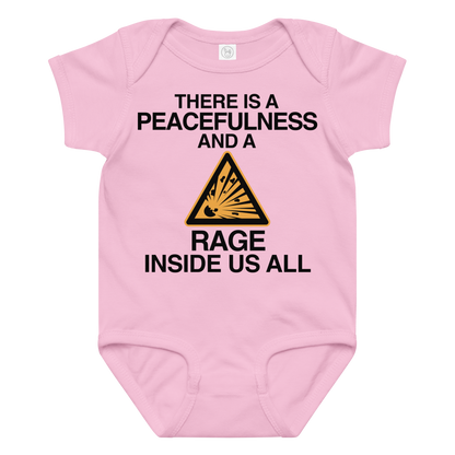 "There is a peacefulness and a rage inside us all" printed on a pink baby jersey bodysuit laying on a flat surface amongst other clothes