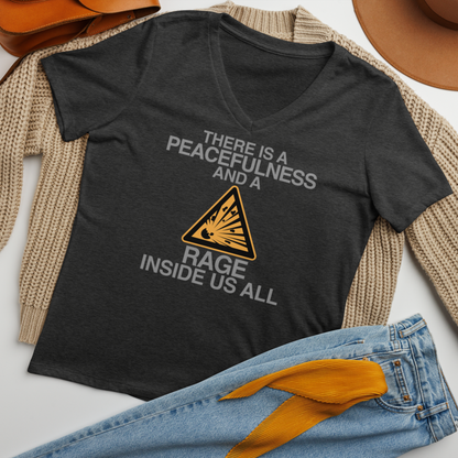 "There is a peacefulness and a rage inside us all" printed on a dark grey heather women's relaxed v-neck t-shirt laying on a flat surface amongst other clothes