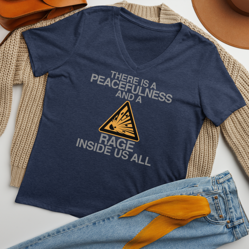 "There is a peacefulness and a rage inside us all" printed on a heather navy women's relaxed v-neck t-shirt laying on a flat surface amongst other clothes