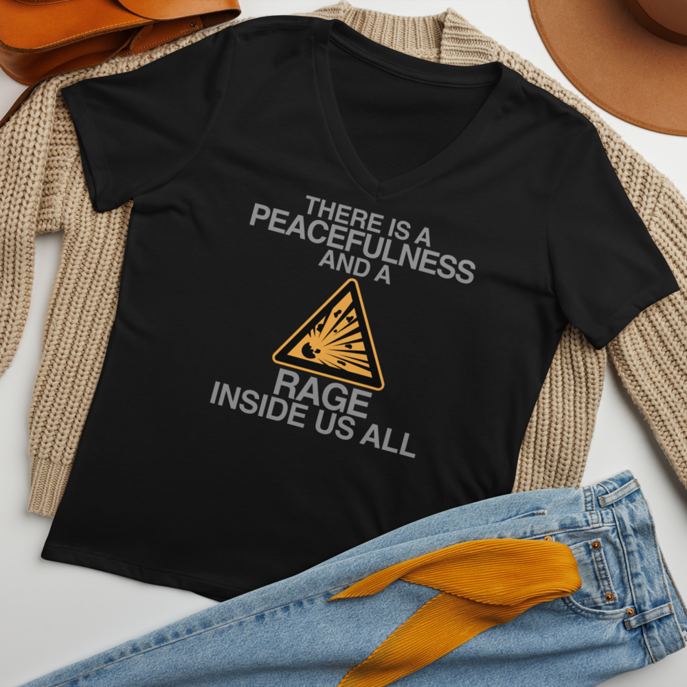 "There is a peacefulness and a rage inside us all" printed on a solid black blend women's relaxed v-neck t-shirt laying on a flat surface amongst other clothes
