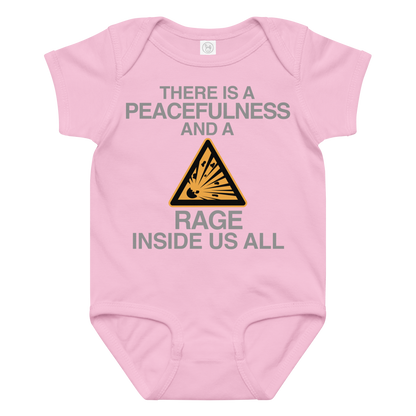"There is a peacefulness and a rage inside us all" printed on a pink baby jersey bodysuit laying on a flat surface amongst other clothes