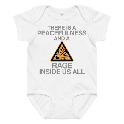 "There is a peacefulness and a rage inside us all" printed on a white baby jersey bodysuit laying on a flat surface amongst other clothes
