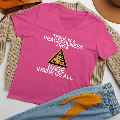 "There is a peacefulness and a rage inside us all" printed on a berry women's relaxed v-neck t-shirt laying on a flat surface amongst other clothes