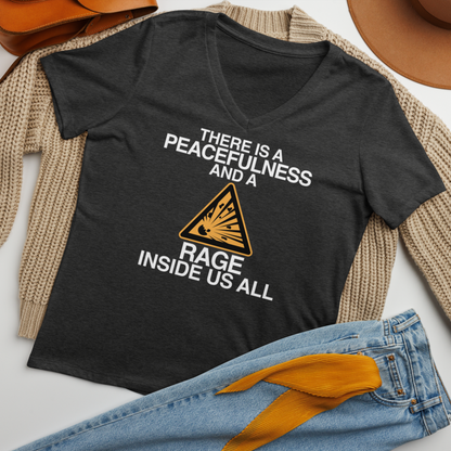 "There is a peacefulness and a rage inside us all" printed on a dark grey heather women's relaxed v-neck t-shirt laying on a flat surface amongst other clothes