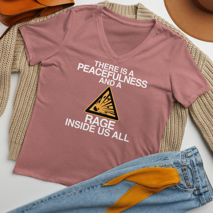 "There is a peacefulness and a rage inside us all" printed on a heather mauve women's relaxed v-neck t-shirt laying on a flat surface amongst other clothes