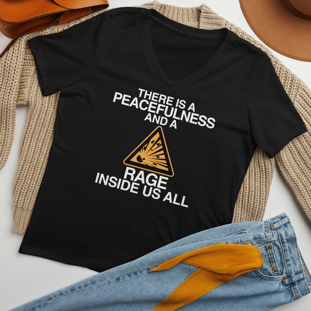 "There is a peacefulness and a rage inside us all" printed on a solid black blend women's relaxed v-neck t-shirt laying on a flat surface amongst other clothes