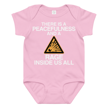 "There is a peacefulness and a rage inside us all" printed on a pink baby jersey bodysuit laying on a flat surface amongst other clothes