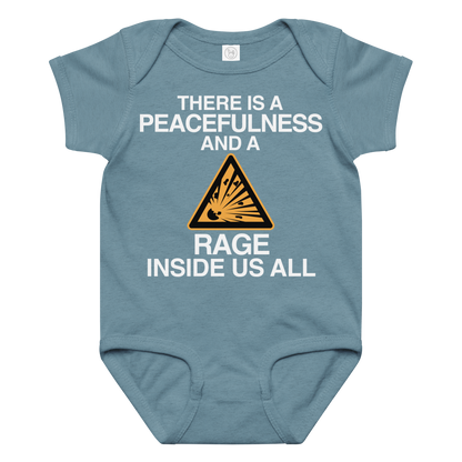 "There is a peacefulness and a rage inside us all" printed on a vintage indigo baby jersey bodysuit laying on a flat surface amongst other clothes