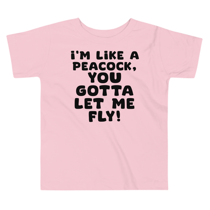 "I'm like a peacock, you gotta let me fly!" printed on a pink toddler short sleeve tee laying on a flat surface