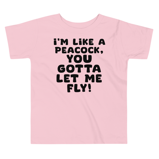 "I'm like a peacock, you gotta let me fly!" printed on a pink toddler short sleeve tee laying on a flat surface