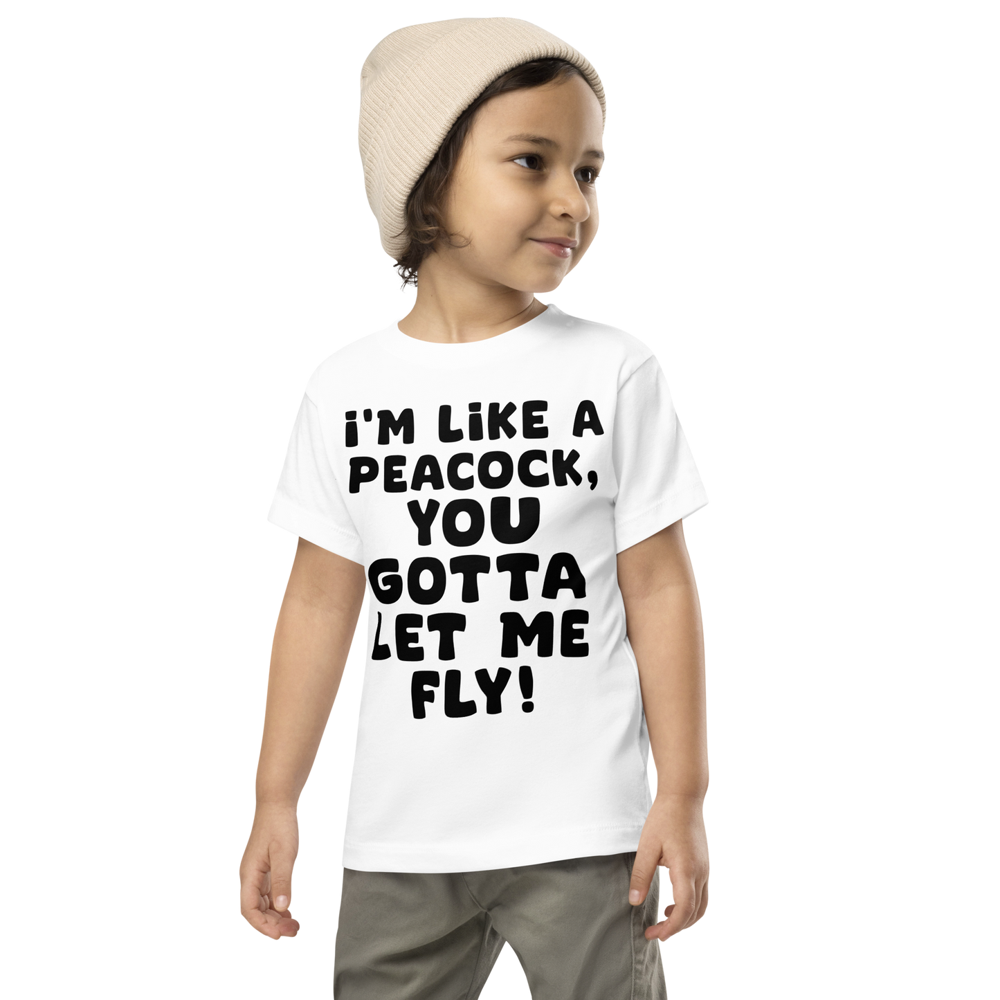 "I'm like a peacock, you gotta let me fly!" printed on a white toddler short sleeve tee worn by a male wearing a cap