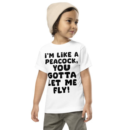 "I'm like a peacock, you gotta let me fly!" printed on a white toddler short sleeve tee worn by a male wearing a cap
