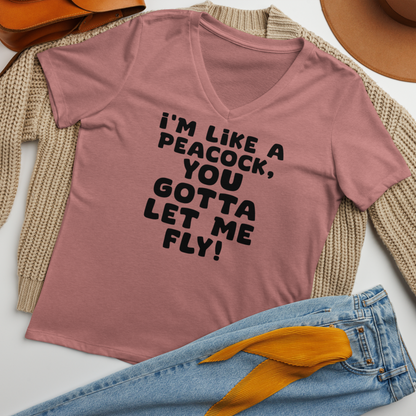 "I'm like a peacock, you gotta let me fly!" printed on a heather mauve women's relaxed v-neck t-shirt laying on a flat surface amongst other clothes
