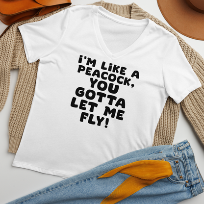 "I'm like a peacock, you gotta let me fly!" printed on a solid white blend women's relaxed v-neck t-shirt laying on a flat surface amongst other clothes