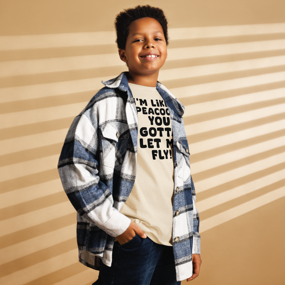 "I'm like a peacock, you gotta let me fly!" printed on a natural youth classic tee worn by a male also wearing a jacket