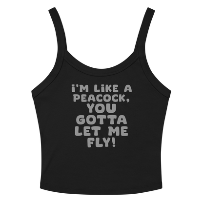 "I'm like a peacock, you gotta let me fly!" printed on a solid black blend women's micro-rib tanktop laying on a flat surface amongst sunglasses and shorts