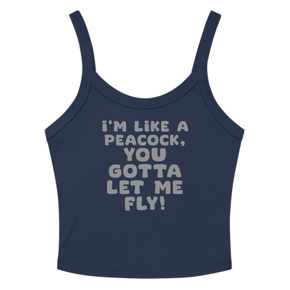 "I'm like a peacock, you gotta let me fly!" printed on a solid navy blend women's micro-rib tanktop laying on a flat surface amongst sunglasses and shorts