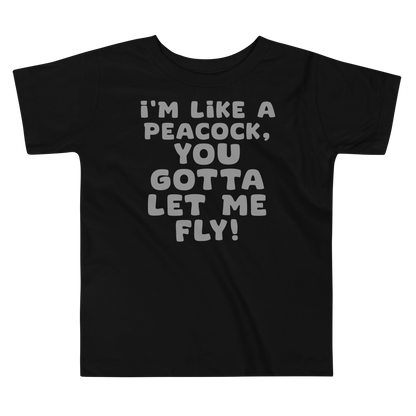 "I'm like a peacock, you gotta let me fly!" printed on a black toddler short sleeve tee laying on a flat surface