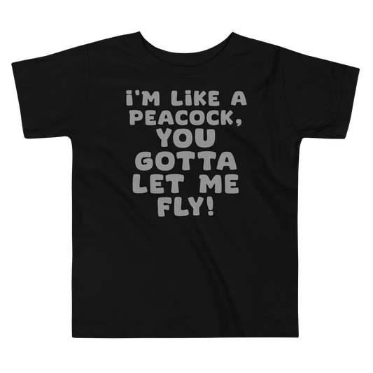 "I'm like a peacock, you gotta let me fly!" printed on a black toddler short sleeve tee laying on a flat surface