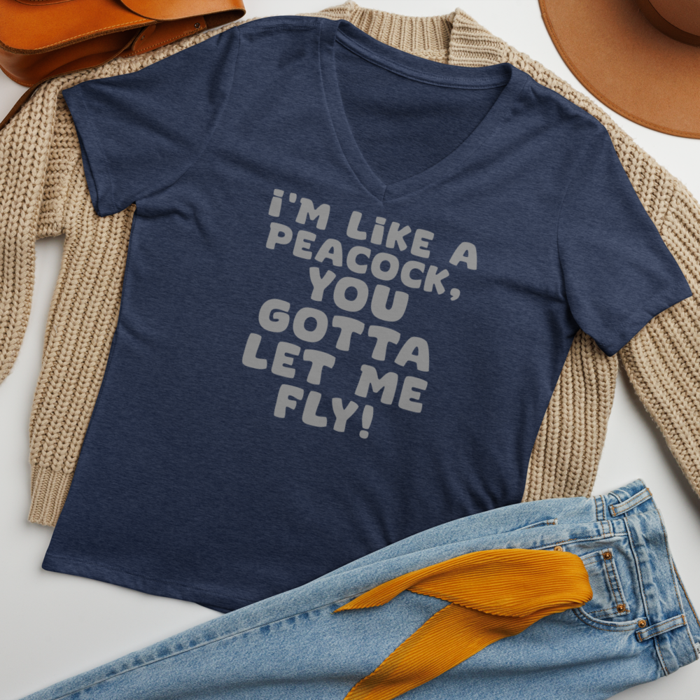"I'm like a peacock, you gotta let me fly!" printed on a heather navy women's relaxed v-neck t-shirt laying on a flat surface amongst other clothes