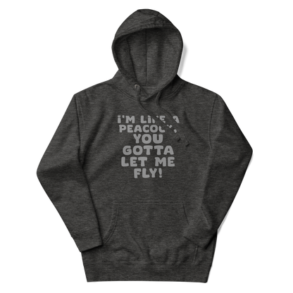 "I'm like a peacock, you gotta let me fly!" printed on a charcoal heather unisex hoodie laying on a flat surface with the hood up