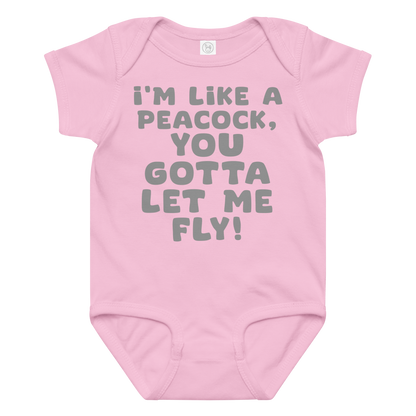 "I'm like a peacock, you gotta let me fly!" printed on a pink baby jersey bodysuit laying on a flat surface amongst other clothes